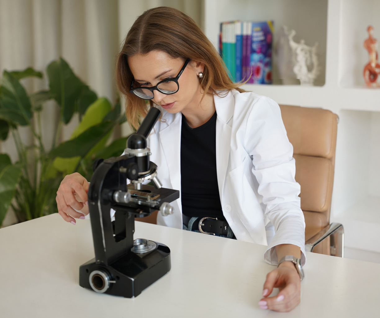 Ela w fartuchu laboratoryjnym pracuje przy mikroskopie podczas studiów biologicznych